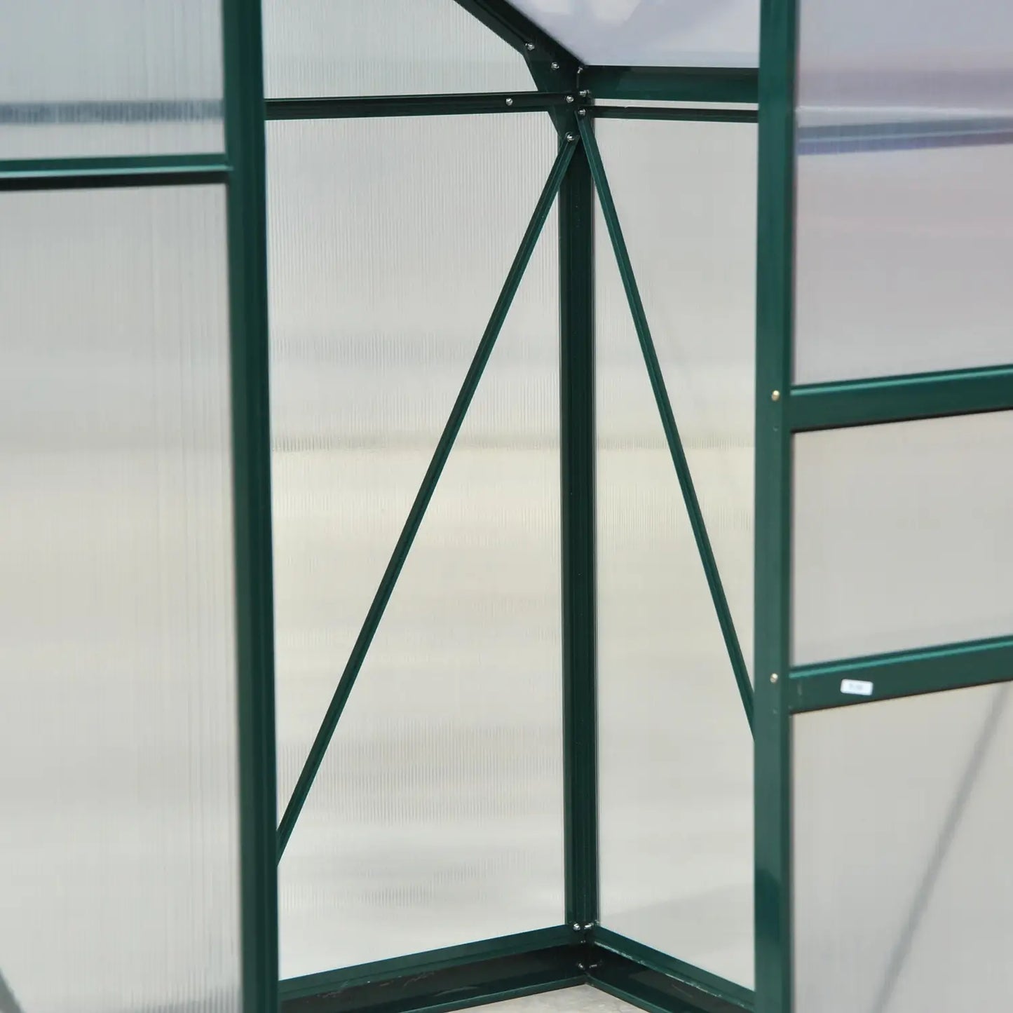 Green metal frame of a greenhouse with transparent panels