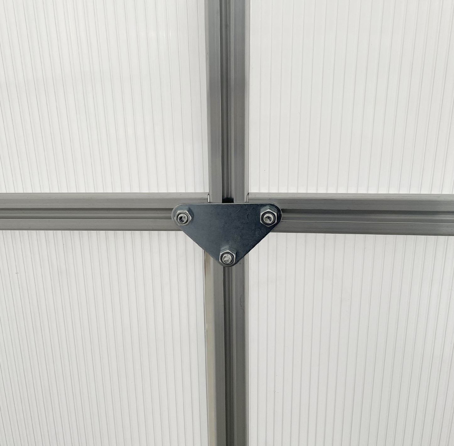 Close-up of a corner connection with metal brackets on a greenhouse