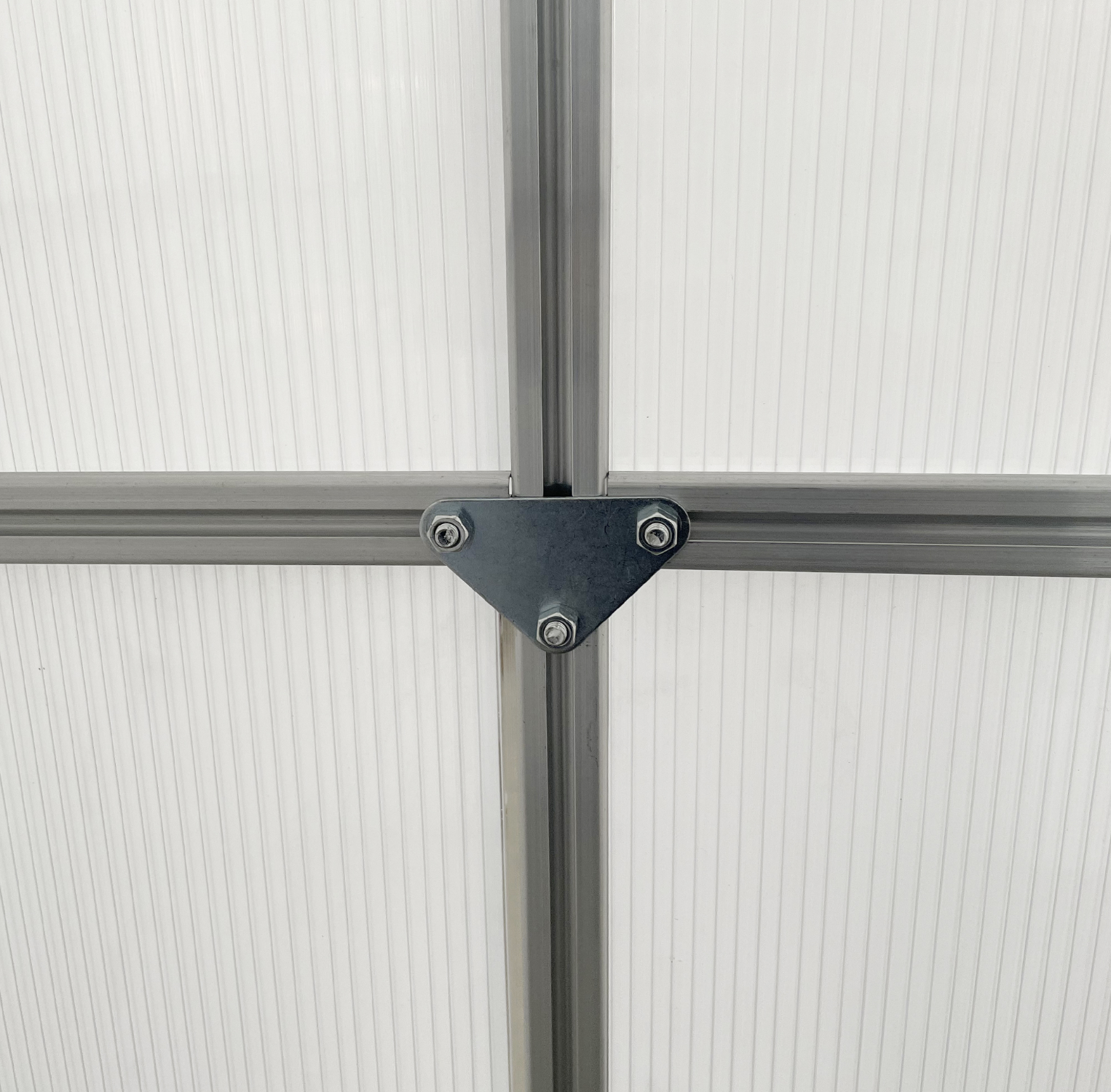 Close-up of a corner connection with metal brackets on a greenhouse