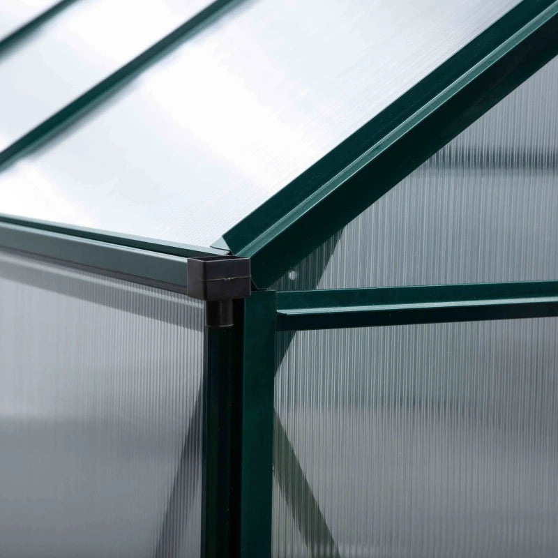 Close-up of a corner of a greenhouse with green metal frame and transparent panels.