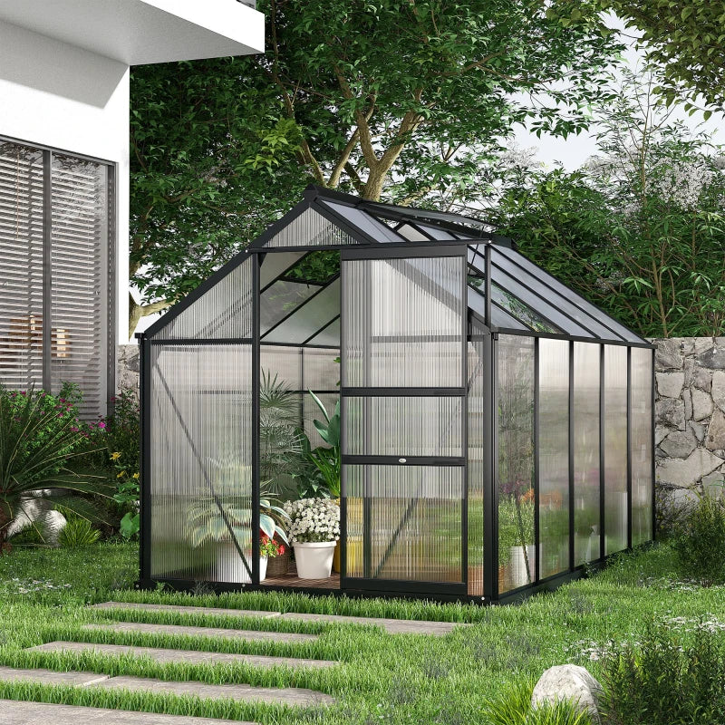 Greenhouse in a garden setting with a house and trees in the background
