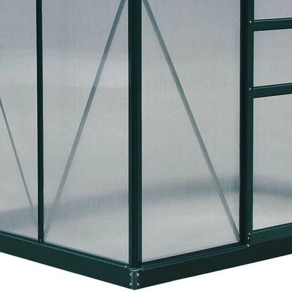 Corner of a greenhouse with transparent panels and green metal frame