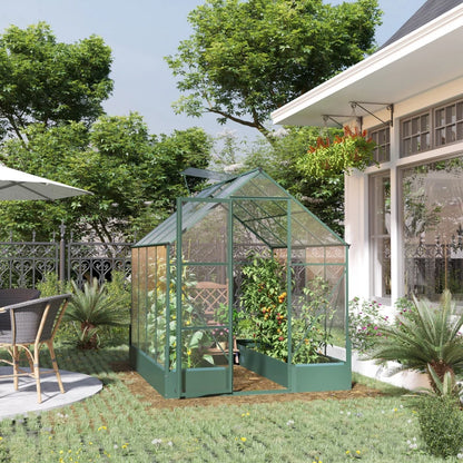 Green greenhouse in a garden with a house and trees in the background