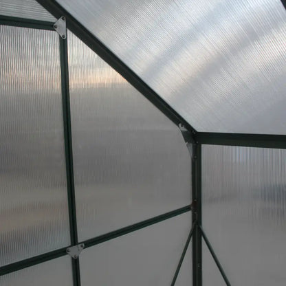Greenhouse structure with transparent polycarbonate panels and metal frame.